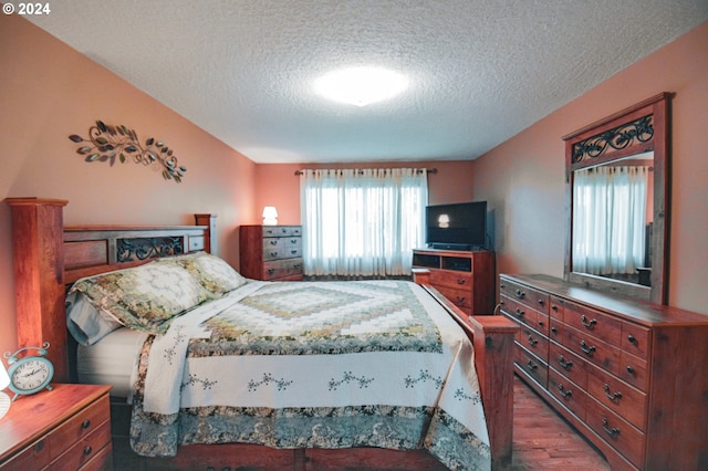 bedroom with a textured ceiling and dark wood-type flooring