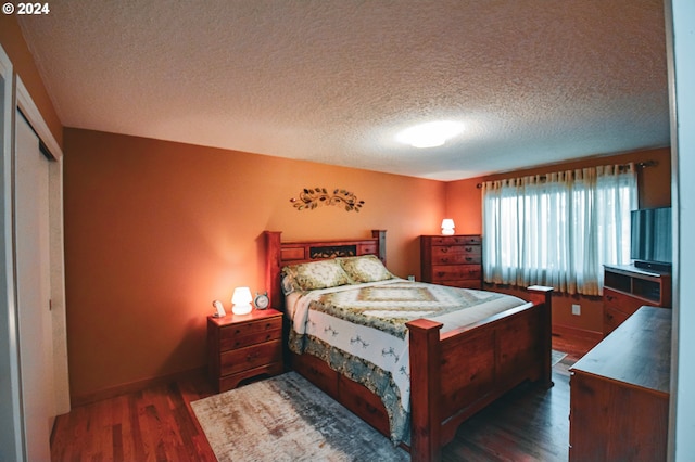 bedroom with a textured ceiling, dark hardwood / wood-style flooring, and a closet