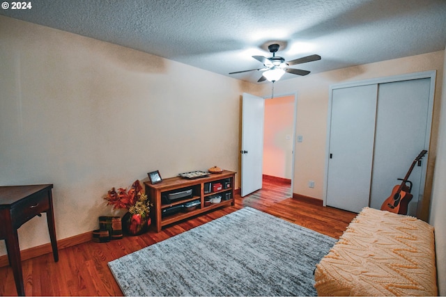 interior space with ceiling fan, a textured ceiling, a closet, and dark hardwood / wood-style flooring