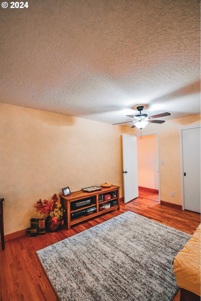 interior space with a textured ceiling, hardwood / wood-style flooring, and ceiling fan