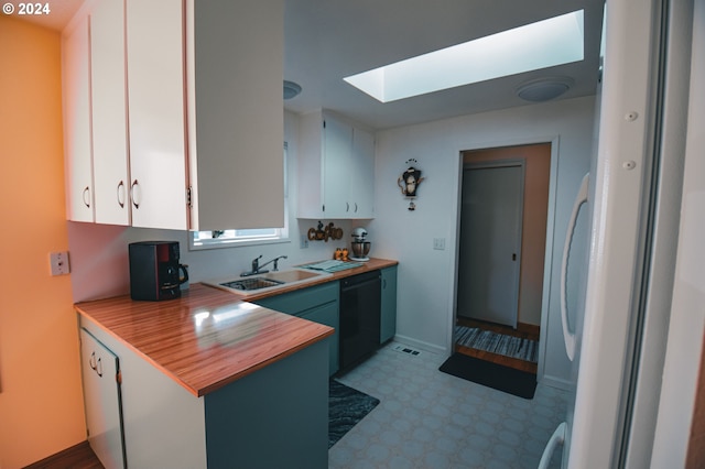 kitchen featuring a skylight, dishwasher, sink, and white cabinetry