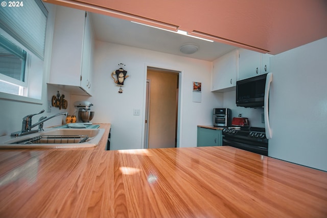 kitchen with black appliances, white cabinetry, and sink