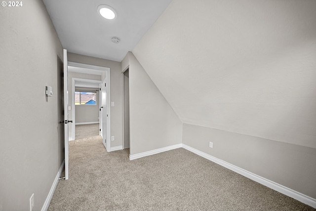 additional living space with light carpet and vaulted ceiling