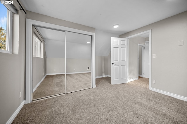 unfurnished bedroom featuring carpet floors, a closet, and vaulted ceiling