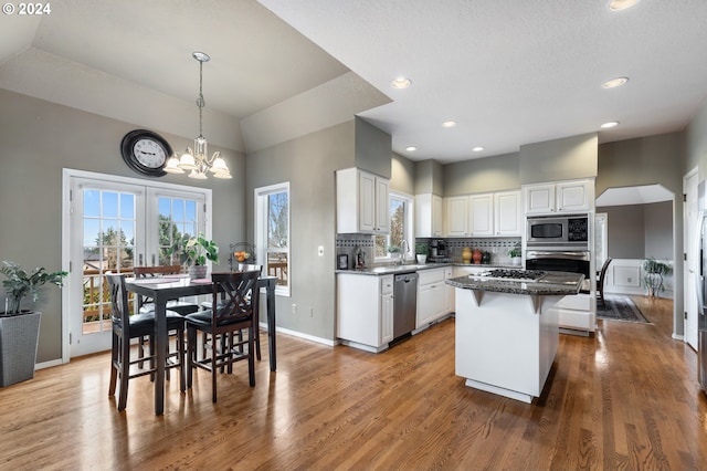 kitchen featuring a center island, white cabinets, lofted ceiling, and appliances with stainless steel finishes