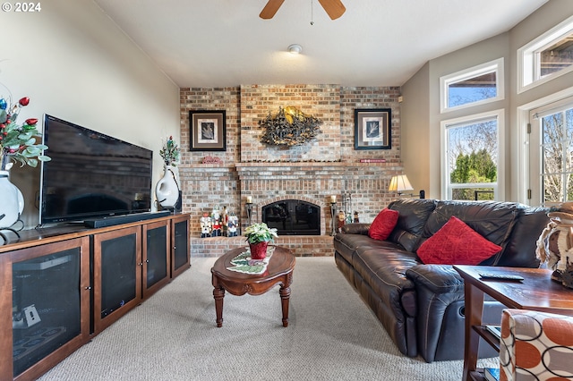 carpeted living room with a fireplace, ceiling fan, and brick wall