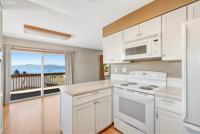 kitchen with white cabinetry, a water and mountain view, white appliances, and kitchen peninsula