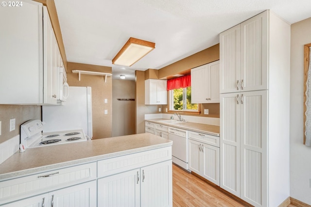 kitchen with white cabinetry, sink, white appliances, and light hardwood / wood-style floors