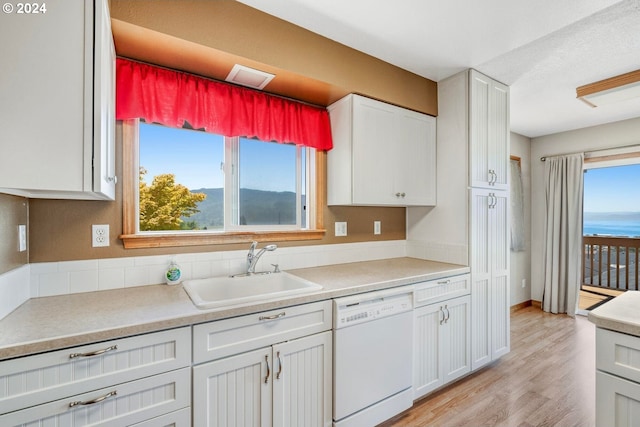 kitchen featuring a healthy amount of sunlight, sink, white cabinets, and dishwasher