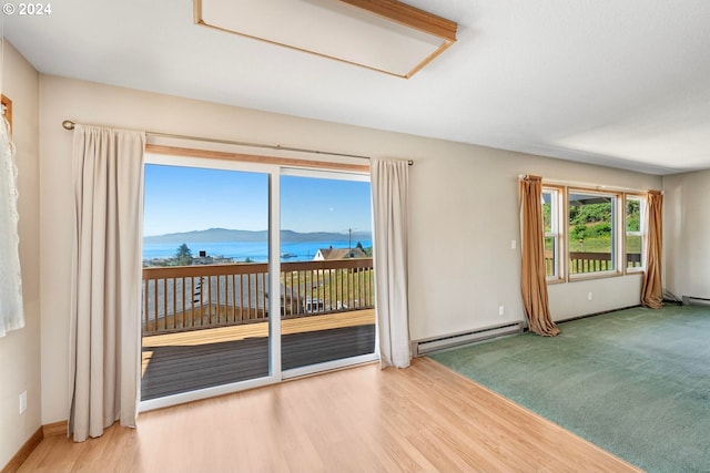 carpeted spare room with a baseboard radiator, plenty of natural light, and a water and mountain view