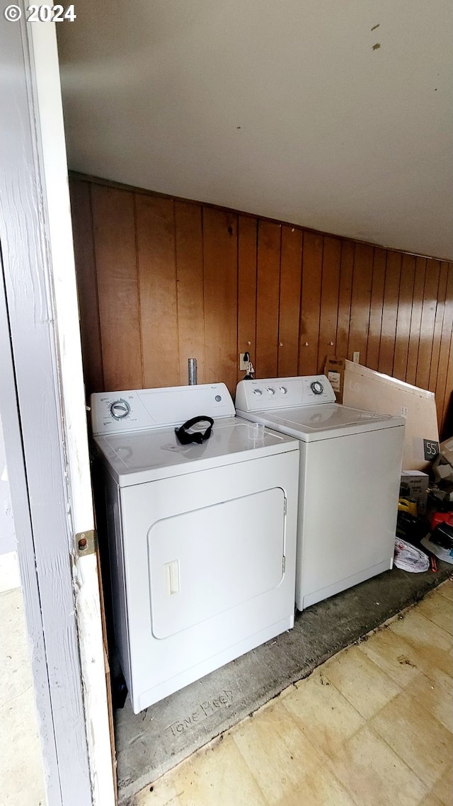 laundry room with wood walls and separate washer and dryer