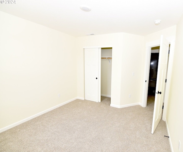 unfurnished bedroom with a closet and light colored carpet