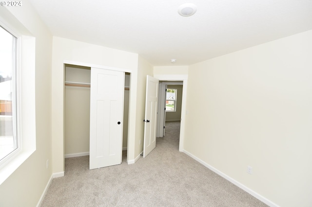 unfurnished bedroom featuring a closet and light carpet