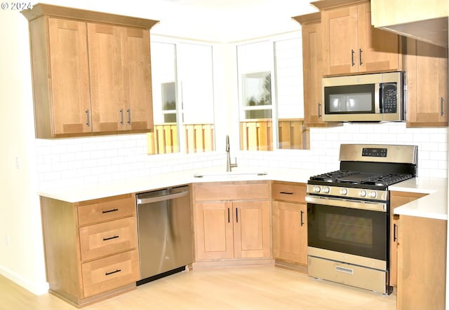 kitchen featuring sink, light hardwood / wood-style floors, stainless steel appliances, and backsplash