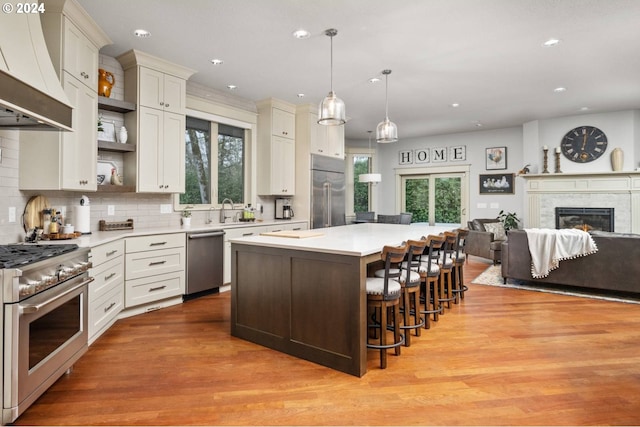 kitchen featuring open shelves, high quality appliances, light countertops, custom exhaust hood, and a sink