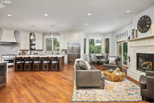 living area featuring a wealth of natural light, light wood-style floors, a lit fireplace, and recessed lighting