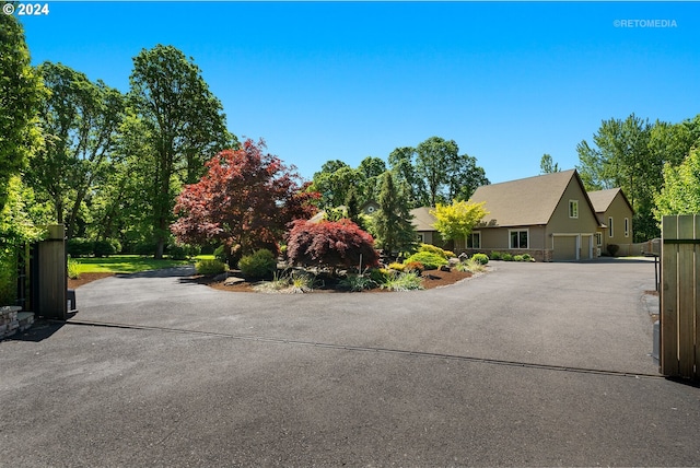 view of front facade with aphalt driveway, a gate, fence, and a garage