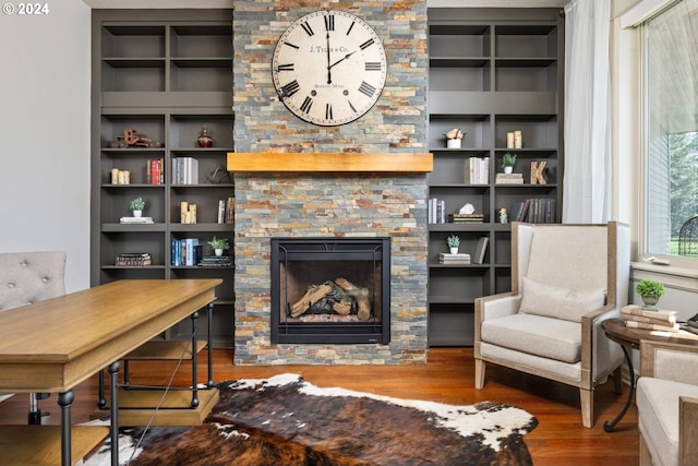 living area with a stone fireplace and wood finished floors