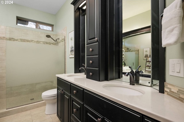 bathroom featuring double vanity, a tile shower, and a sink