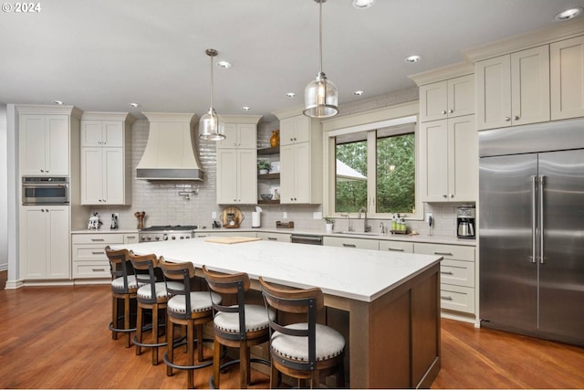 kitchen featuring a center island, dark wood-style floors, custom exhaust hood, stainless steel appliances, and a sink