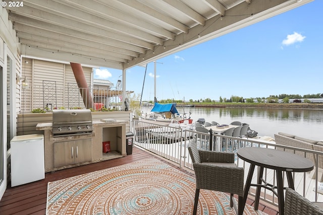 view of patio / terrace with area for grilling, a water view, and exterior kitchen