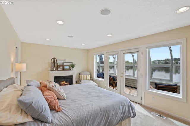 carpeted bedroom with a water view and access to exterior