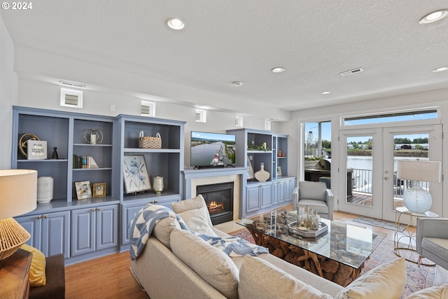 living room with french doors, light hardwood / wood-style flooring, and a textured ceiling