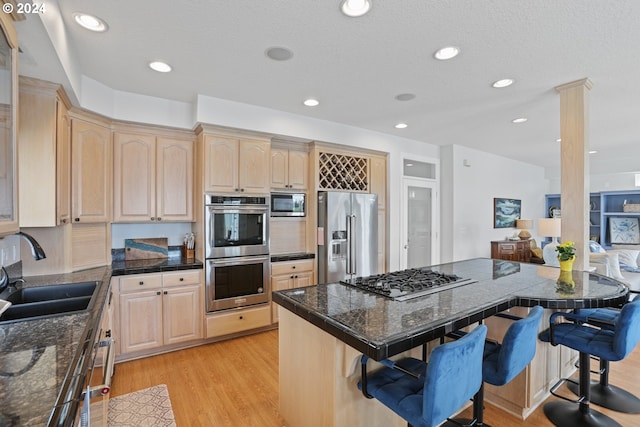 kitchen with sink, light hardwood / wood-style floors, stainless steel appliances, and a breakfast bar area