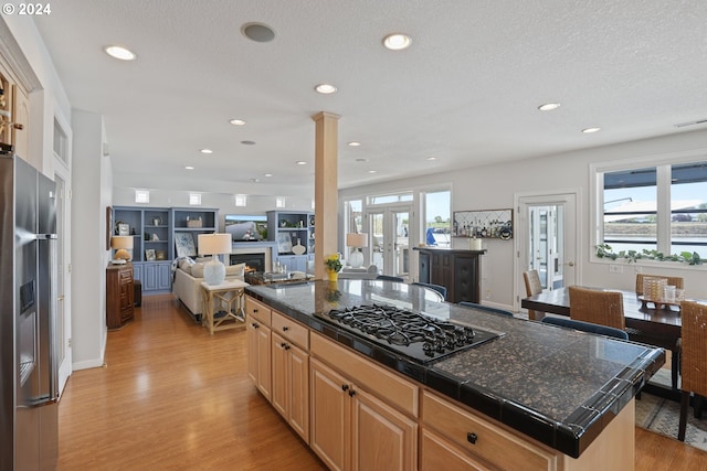 kitchen with french doors, stainless steel fridge with ice dispenser, a kitchen island, black gas cooktop, and light wood-type flooring