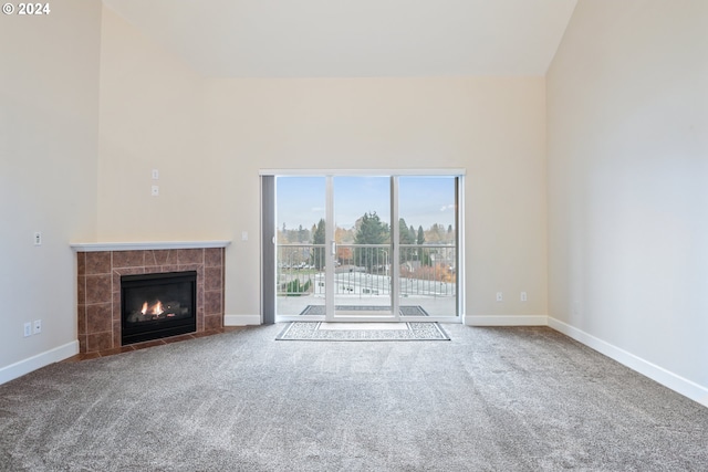 unfurnished living room featuring carpet flooring, lofted ceiling, and a tiled fireplace