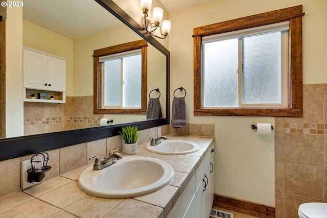 bathroom with a wealth of natural light, double sink, and toilet