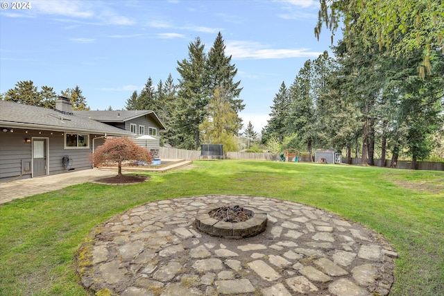 view of yard featuring a patio area, a fire pit, and a trampoline