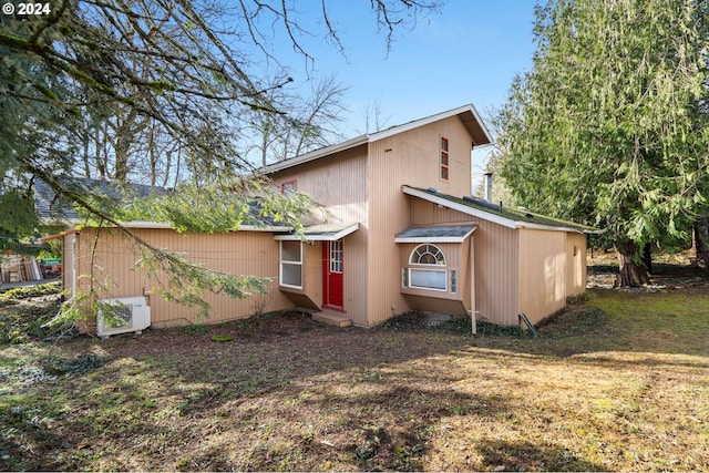 rear view of property featuring ac unit and a lawn