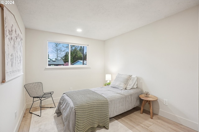 bedroom featuring a textured ceiling and light hardwood / wood-style floors