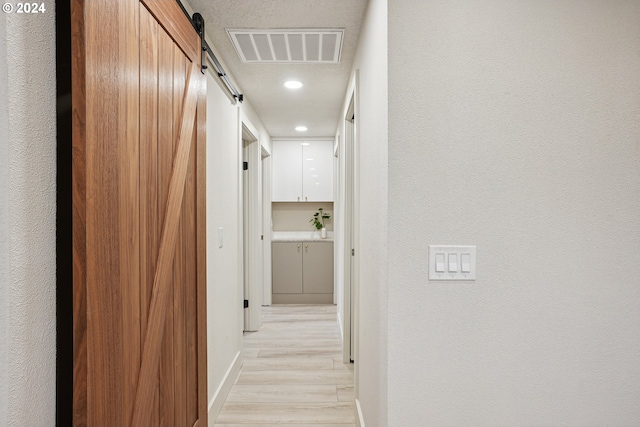 hall with light hardwood / wood-style floors and a barn door