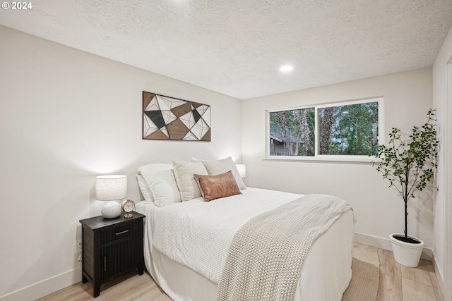 bedroom featuring a textured ceiling and light hardwood / wood-style flooring