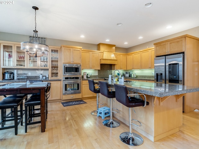 kitchen featuring a center island with sink, sink, light hardwood / wood-style flooring, light brown cabinetry, and stainless steel appliances