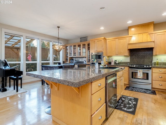 kitchen featuring sink, stainless steel appliances, light hardwood / wood-style floors, a breakfast bar area, and a kitchen island with sink