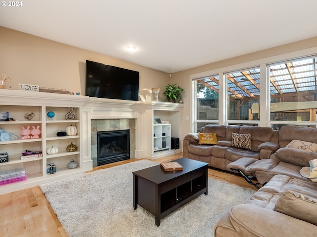 living room featuring wood-type flooring and a tiled fireplace