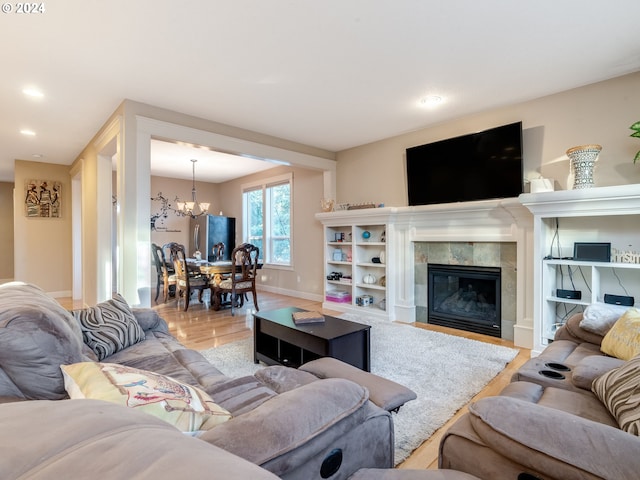 living room with a tile fireplace, light hardwood / wood-style flooring, and a notable chandelier