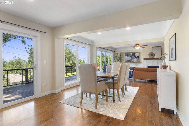 dining room featuring a large fireplace, dark hardwood / wood-style floors, and ceiling fan