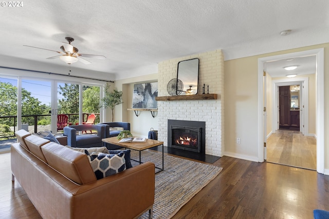 living room with a fireplace, dark hardwood / wood-style flooring, a textured ceiling, and ceiling fan