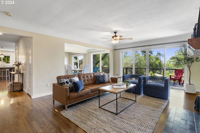 living room featuring a healthy amount of sunlight, ceiling fan, dark wood-type flooring, and a textured ceiling