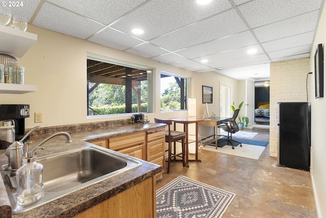 kitchen with concrete floors, a drop ceiling, and sink