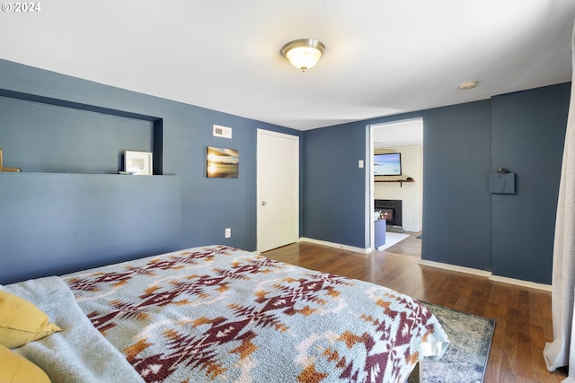 bedroom featuring a fireplace and dark hardwood / wood-style flooring