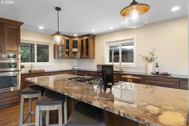 kitchen featuring decorative light fixtures, dark hardwood / wood-style flooring, stainless steel appliances, and dark stone counters