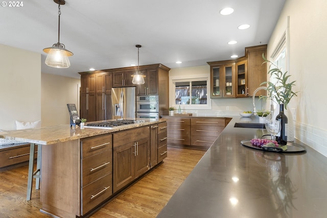 kitchen featuring sink, stainless steel appliances, a kitchen breakfast bar, light hardwood / wood-style flooring, and a kitchen island