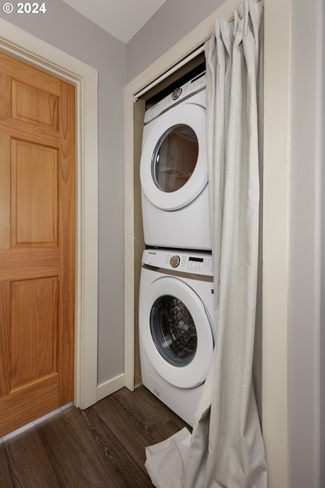 laundry area featuring stacked washer / drying machine and dark hardwood / wood-style flooring