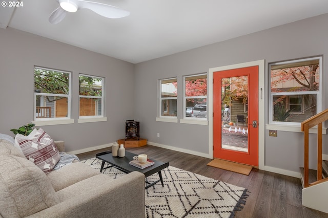 living room with a wood stove, plenty of natural light, dark wood-type flooring, and ceiling fan