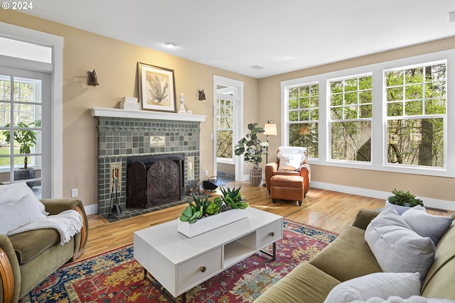 living room with light wood-type flooring and a tiled fireplace